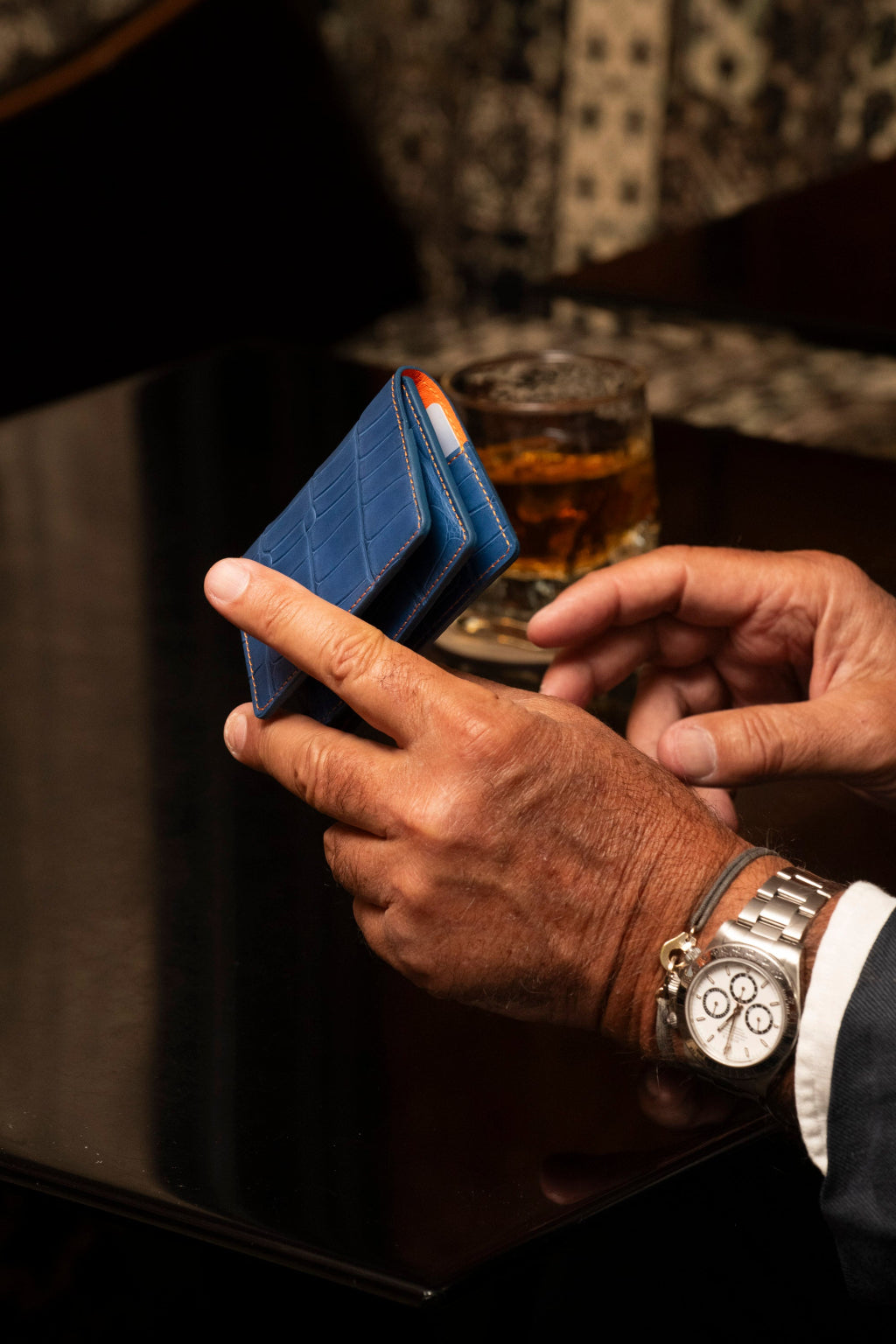 Porte-cartes artisanal Le10Colonne en cuir exotique bleu et coutures oranges présenté en situation lifestyle