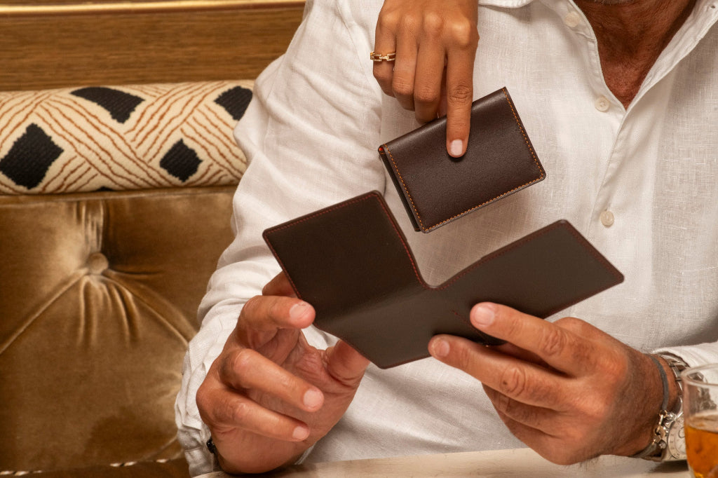 Porte-cartes artisanal Le10Colonne en cuir marron et coutures oranges présenté en situation lifestyle